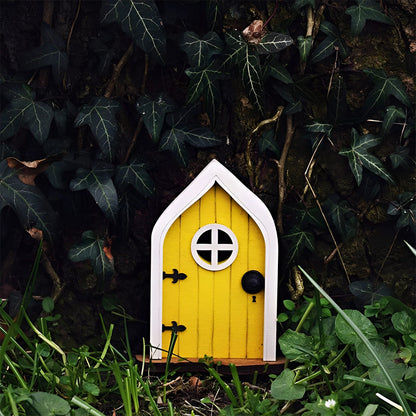 Miniature fairy garden door crafted to resemble an enchanted tree, featuring intricate wooden details, small windows, and surrounded by grass and plants.